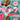 Close-up of the Little Debbie Mini Donuts Beach Towel featuring colorful donuts, tropical leaves, and flowers. The Mini Donuts and Little Debbie logos are centered. Pink flip-flops, nail files, and red sunglasses are placed on the towel.