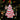 A Little Debbie Christmas Tree Cake® Ornament featuring white frosting with red icing stripes and green sprinkles, hanging by a red ribbon on a Christmas tree with twinkling lights in the background.
