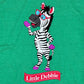 Detail view of a green Little Debbie T-shirt featuring a full body image of Zain the Zebra waving, positioned above the Little Debbie Ribbon logo.
