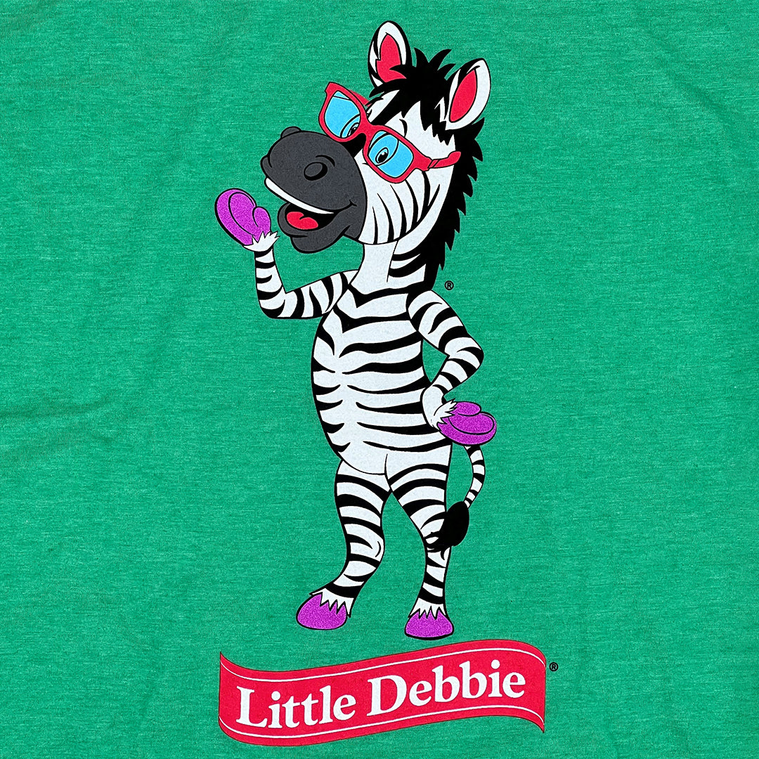 Detail view of a green Little Debbie T-shirt featuring a full body image of Zain the Zebra waving, positioned above the Little Debbie Ribbon logo.