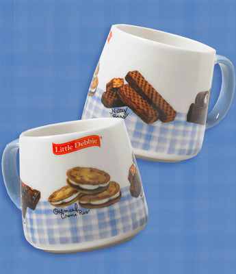 A Little Debbie gingham mug featuring a charming snack-themed design. Each white mug is accented with a light blue gingham border near the bottom and a matching light blue handle. The design showcases illustrations of Little Debbie snacks, including Oatmeal Creme Pies, Nutty Buddy Bars, Cosmic Brownies, and Swiss Rolls, with their names written in cursive. The red Little Debbie logo is prominently displayed near the top of the mug. 