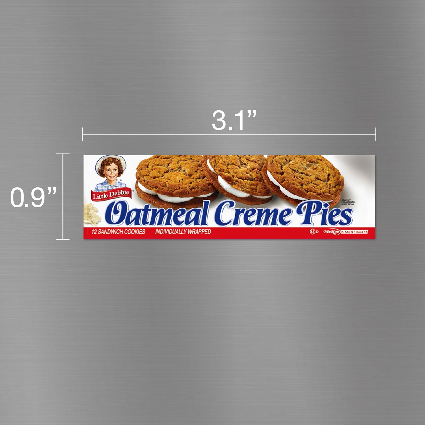 Image of a Little Debbie Oatmeal Creme Pies carton magnet, measuring 3.1 inches wide and 0.9 inches tall. The magnet features a clean silver background with images of three oatmeal creme pies and the iconic Little Debbie logo at the top left corner. The text 'Oatmeal Creme Pies' is prominently displayed in blue and red, indicating the product contains 12 sandwich cookies, individually wrapped.