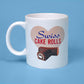 White ceramic mug featuring a graphic of a large heart with 'Swiss Cake Rolls' text in bold blue and red letters. Below the text, there's a realistic image of a Swiss Cake Roll, showing its chocolate coating and spiral cream filling. The mug is displayed against a light blue background.