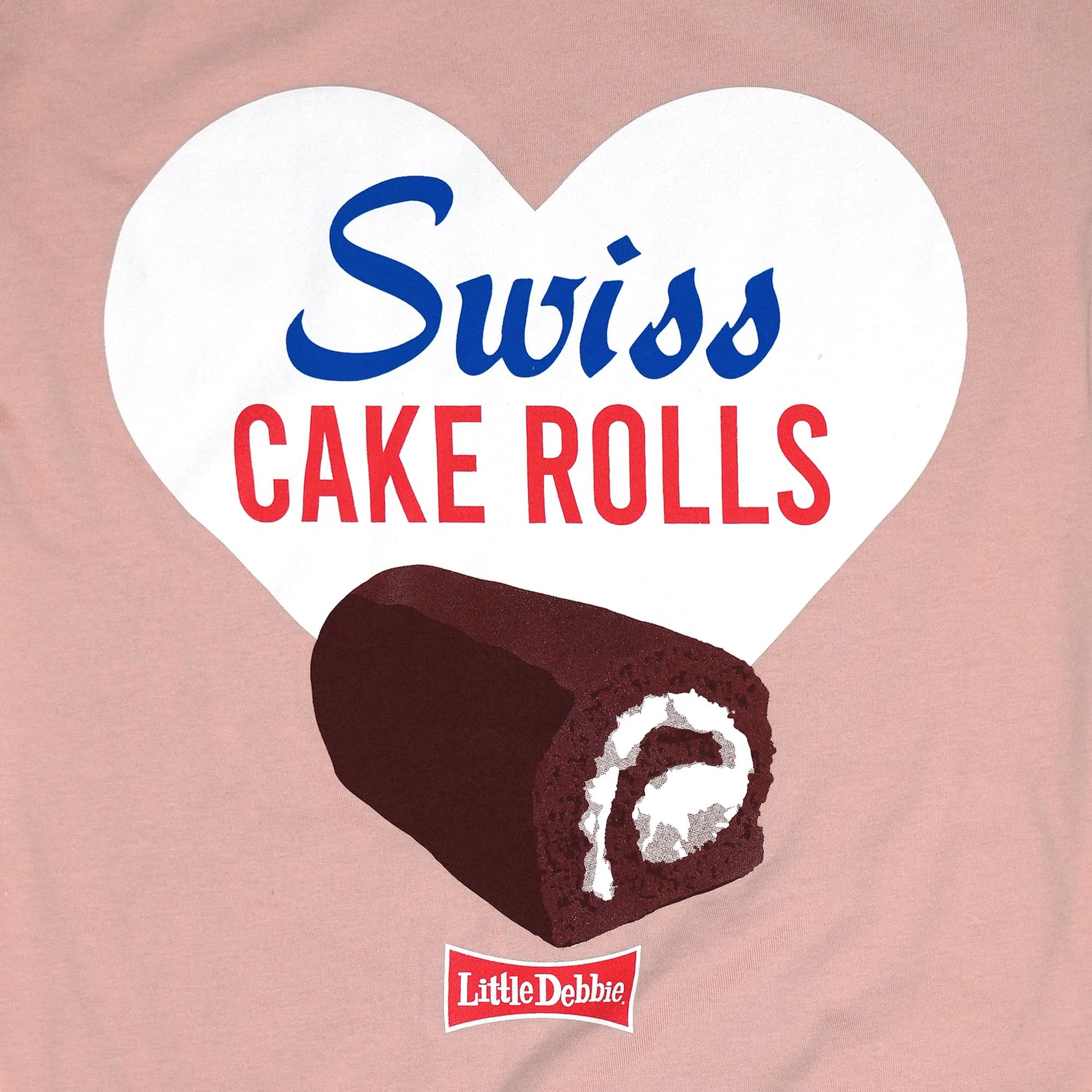 Close-up view of a graphic on a pink t-shirt featuring a large white heart with the text 'Swiss Cake Rolls' in blue and red. Inside the heart, there's an illustrated Swiss Cake Roll with a chocolate exterior and white cream swirl visible in the cross-section. A small red Little Debbie logo is placed at the bottom of the heart.