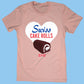 Light pink t-shirt featuring a large heart-shaped design with 'Swiss Cake Rolls' text in bold blue and ed letters. Below the text, there's an image of a Swiss Cake Roll with chocolate coating and a white cream swirl. A small Little Debbie logo is displayed at the bottom of the heart. The background is a soft blue.