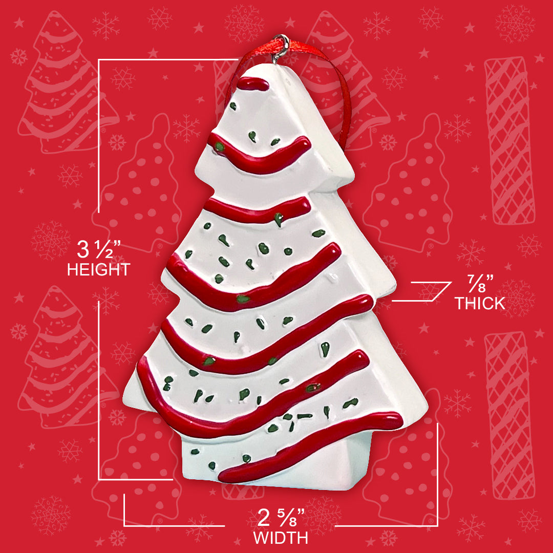 "A close-up of the Little Debbie Christmas Tree Cake ornament, featuring dimensions: 3 1/2 inches in height, 2 5/8 inches in width, and 7/8 inch thick. The ornament, with white icing and red garland details, is accented with green sprinkles and hangs from a red ribbon, set against a red festive background with snowflakes and Christmas Tree Cake shapes.