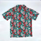 Back view of the Green Little Debbie Hawaiian button up shirt, showcasing a design of red and white Little Debbie Christmas Tree Cakes, Red Ribbon Logos, and an aloha pattern of leaves and flowers.