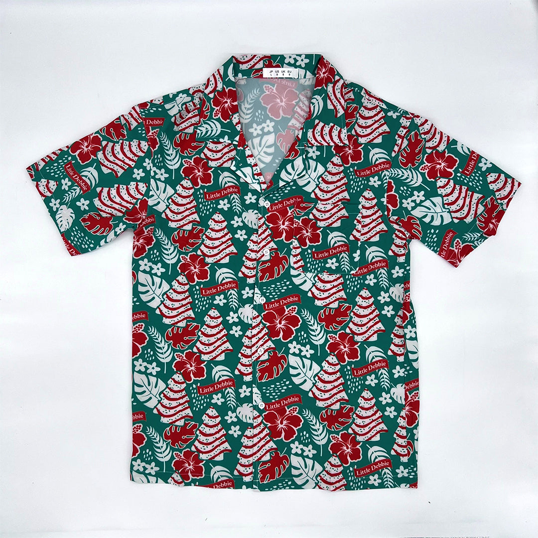 Front view of the Green Little Debbie Hawaiian button up shirt, showcasing a design of red and white Little Debbie Christmas Tree Cakes, Red Ribbon Logos, and an aloha pattern of leaves and flowers.