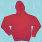 Back view of a red Little Debbie University hoodie with its hood up. It's set against a light blue background patterned with white illustrations of Christmas Trees Cakes, Christmas Tree Brownies, snowflakes, and other winter motifs.