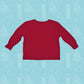 A red Little Debbie® Christmas Tree Cake Taste Tester toddler shirt with long sleeves is centered on a light blue background patterned with white Christmas trees and snowflakes. The shirt is plain, without any visible designs or text, and is laid out flat to show the shape and size suitable for a toddler. 