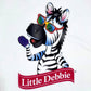 Detail view of a white Little Debbie T-shirt featuring a 1/2 body image of Zain the Zebra waving, positioned above the Little Debbie Ribbon logo.