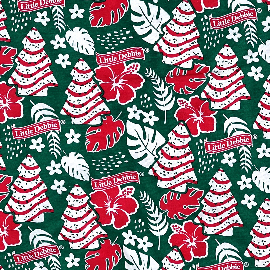 Close-up of Little Debbie Hawaiian Dog shirt showcasing the green Little Debbie Hawaiian pattern, highlighted by red and white designs of Little Debbie Christmas Tree Cakes, Little Debbie Red Ribbon Logos, and an aloha leaf and flower motif.