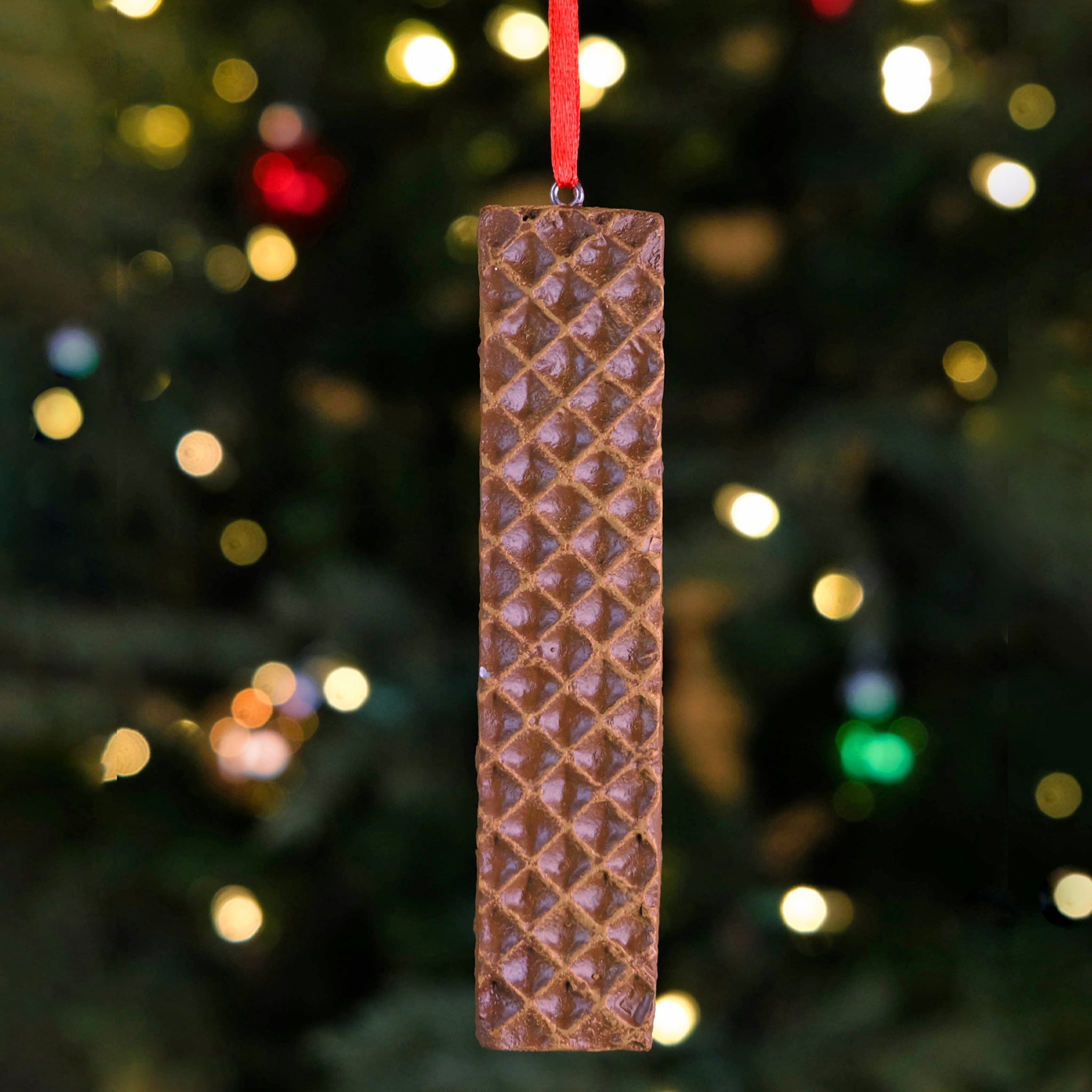 Little Debbie Nutty Buddy Ornament featuring a detailed chocolatey wafer bar design, hanging by a red ribbon in front of a softly lit Christmas tree.